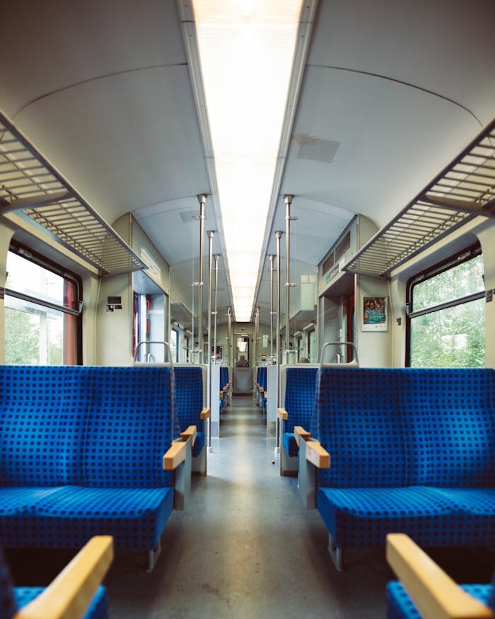 Interior de trem moderno e espaçoso com bancos azuis, ideal para conceitos de transportes públicos.