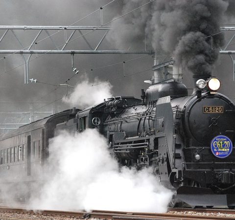 Locomotiva a vapor libertando fumo e vapor numa via férrea, mostrando o transporte ferroviário vintage.