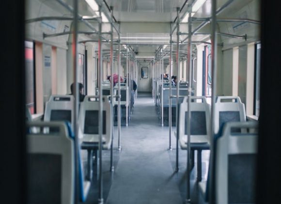 Vista do interior de um trem de viagem moderno com lugares vazios e um design interior limpo.